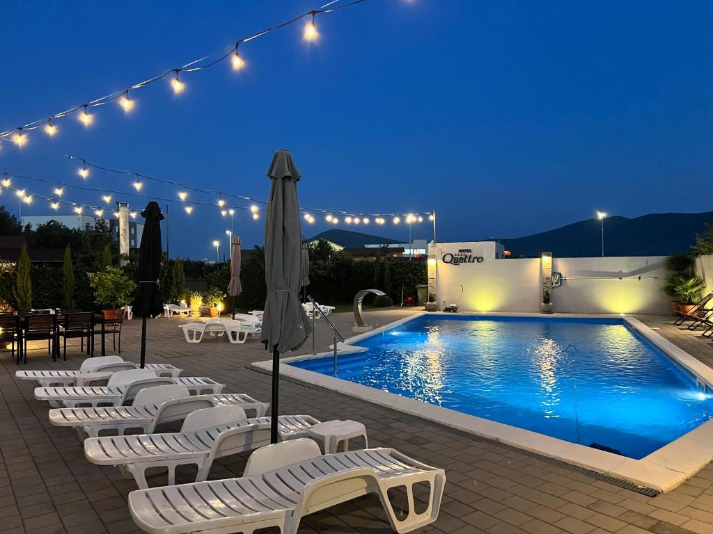 een groep witte stoelen naast een zwembad 's nachts bij Hotel Quattro Medjugorje in Međugorje