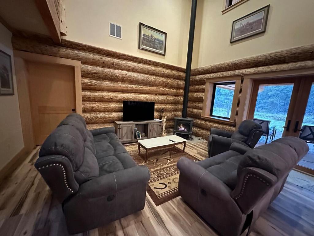 a living room with two couches and a tv at Waterfront Log Cabin - Sunriver in Bend
