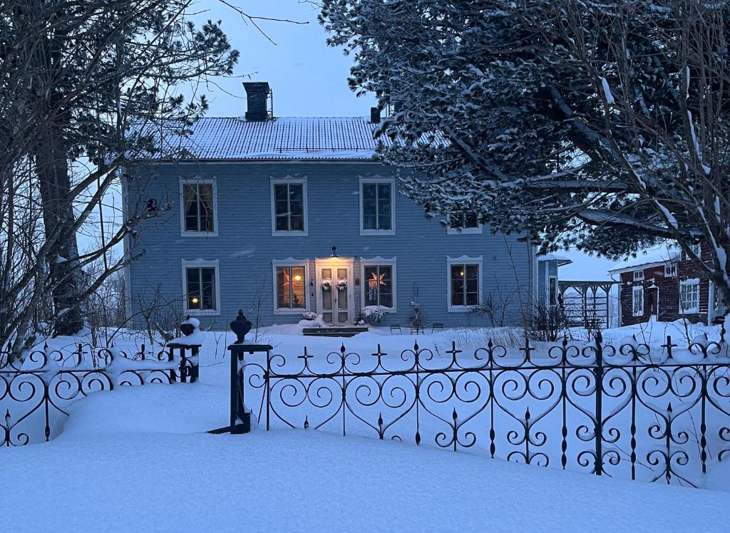 a blue house with a fence in the snow at Norrgården Hälsingland in Vallsta