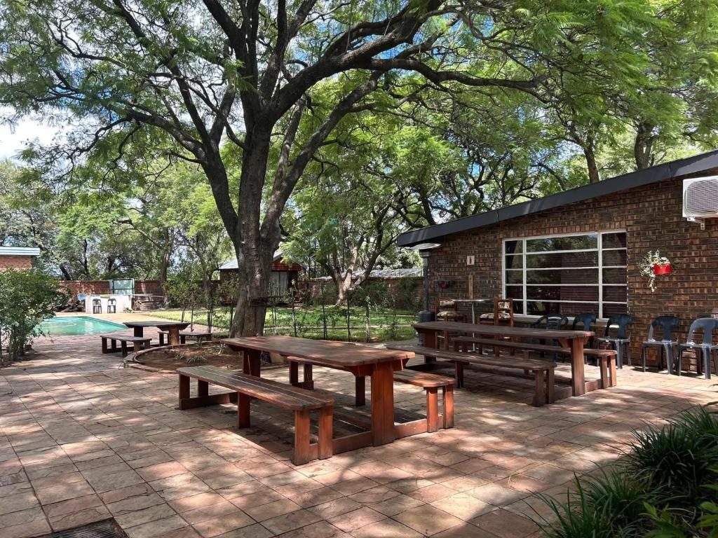 a group of picnic tables in a park with a tree at Kameeldoring Guesthouse in Zeerust