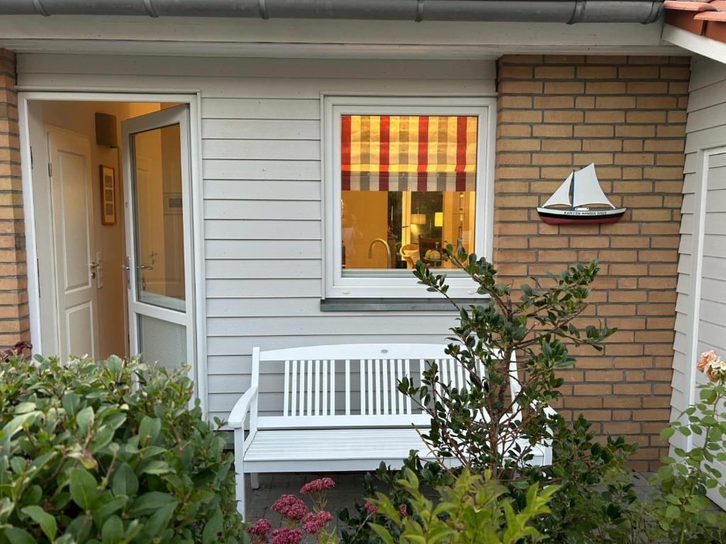 a white bench on the side of a house with a window at Kapitän Hansen Haus in Kosel