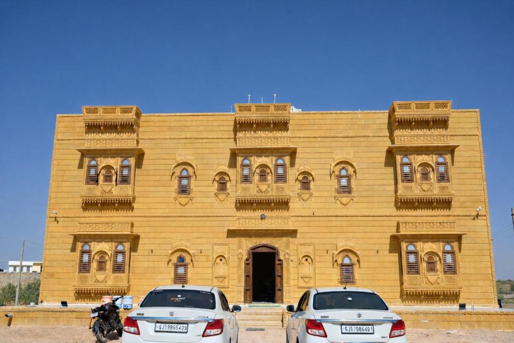 twee auto's geparkeerd voor een houten gebouw bij Hotel Patel Heritage Sam in Sām
