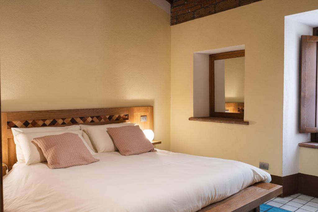 a bedroom with a large white bed with a mirror at Le Dimore by Borgo Tessile - Feronia in Orvieto