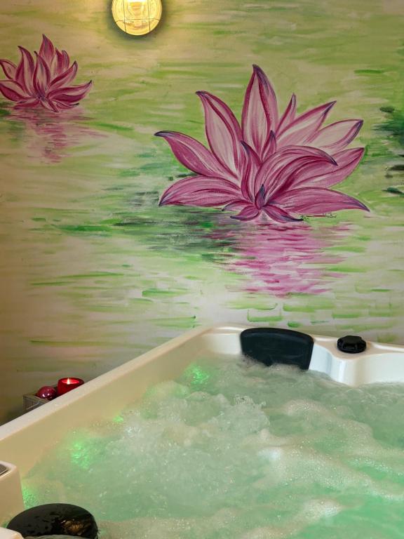 a bath tub with a painting of flowers on a wall at B&B Beauty House in Cesena