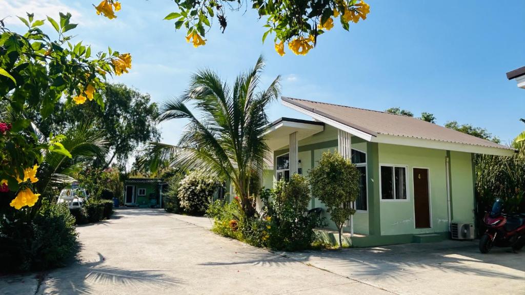 a green house with a palm tree in front of it at ออมทรัพย์ รีสอร์ต in Ban Lam Ta Sao Tai