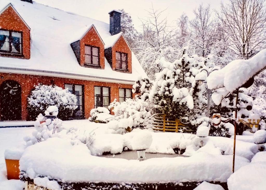 a house covered in snow in front of a yard at Villa Sparadis in Spa