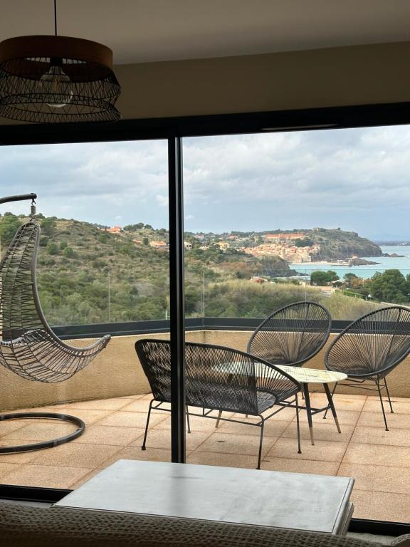 a room with a balcony with chairs and a view of the ocean at Résidence Le Vénusia - 2 in Port-Vendres