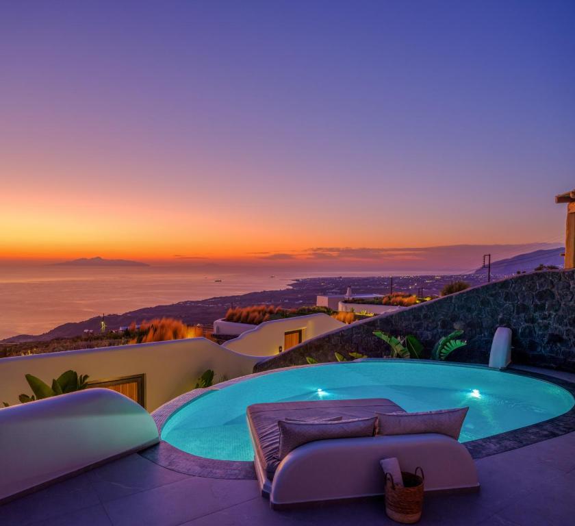 una vasca idromassaggio su un patio con tramonto sullo sfondo di Secret Path Luxury Villas a Imerovigli