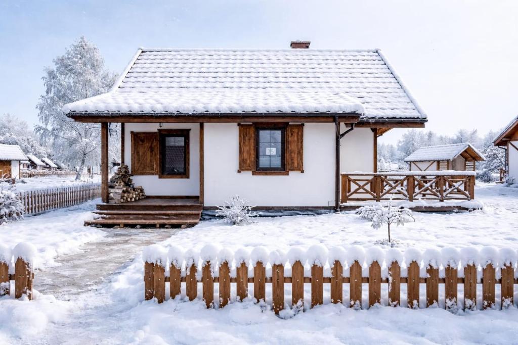 a small house covered in snow with a fence at Warmia Prestige in Woryty