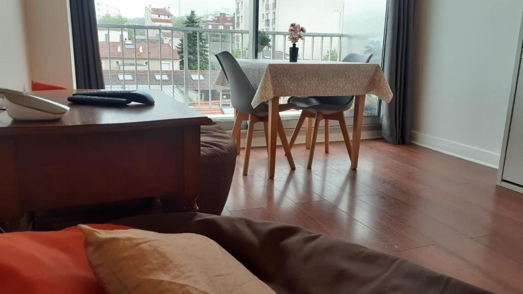 a table and chairs in a living room with a window at LePré Apartment 93 in Le Pré-Saint-Gervais