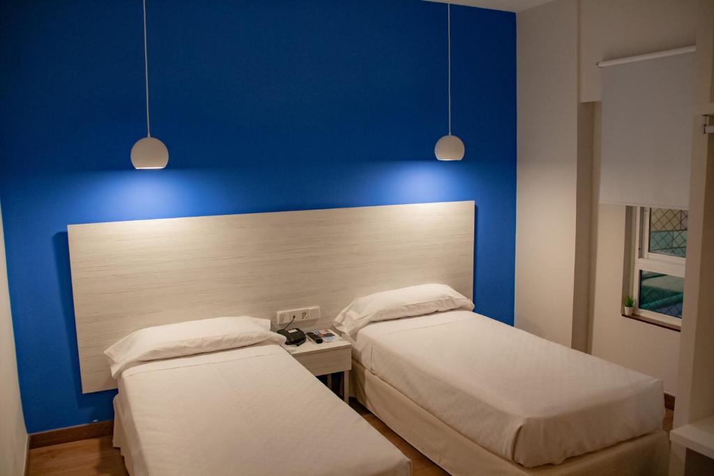 twee bedden in een kamer met een blauwe muur bij Hotel Universal Murcia in Murcia