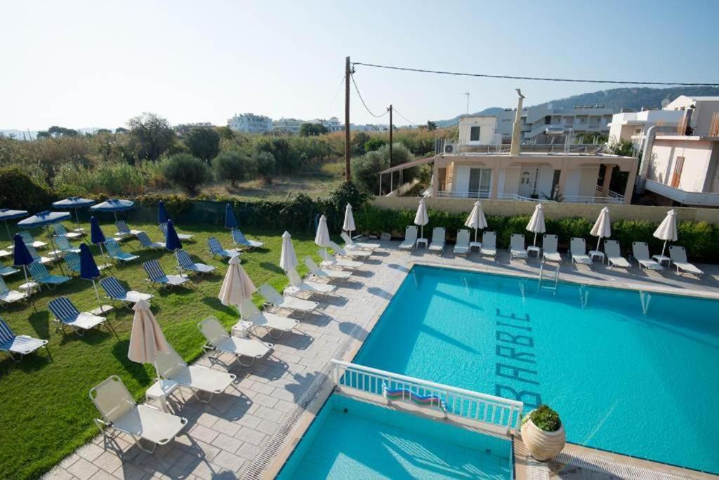 a swimming pool with lounge chairs and umbrellas at Barbie II in Ialysos