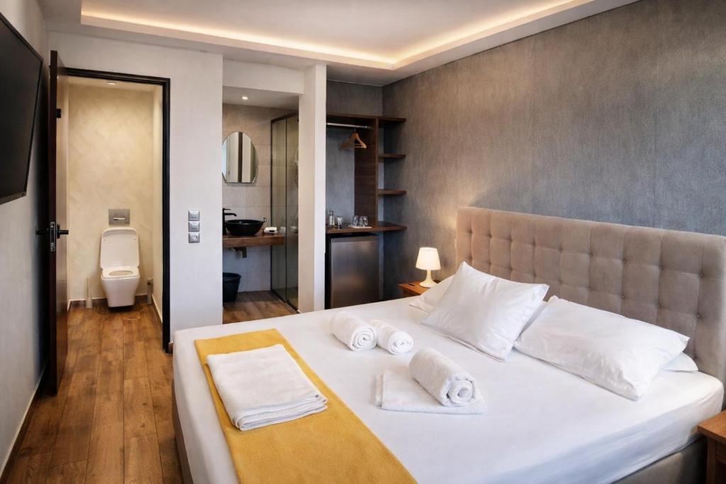 een slaapkamer met een groot wit bed met handdoeken erop bij Villa Park Luxury Rooms in Paralion astros