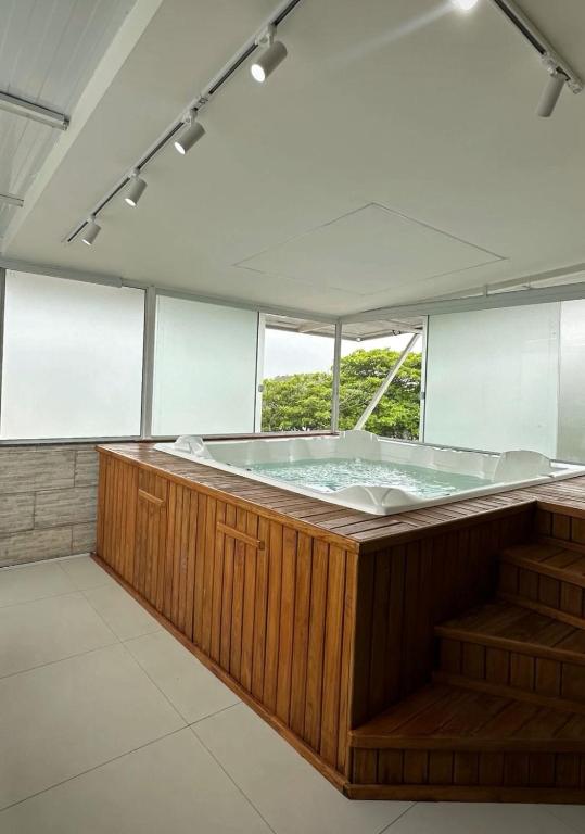 a jacuzzi tub in a room with windows at Casa Premium com Jacuzzi e Churrasqueira in Palhoça