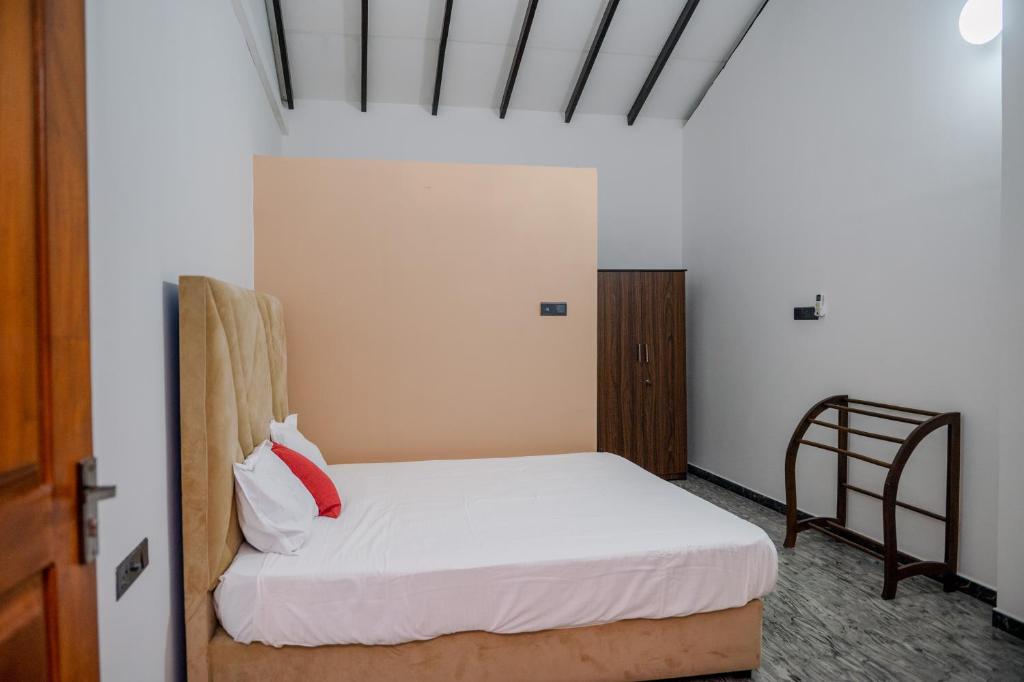 a bedroom with a white bed with a red pillow at French Villa in Dankotuwa