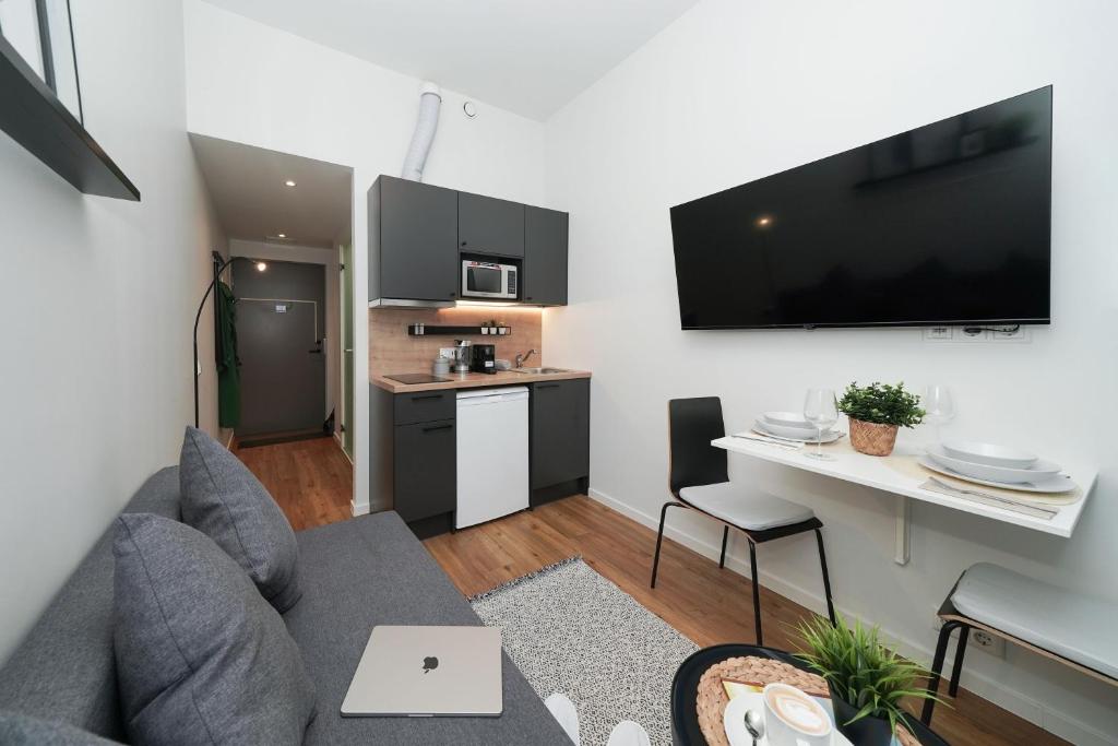 a living room with a gray couch and a kitchen at Stylish smart studio in Tallinn