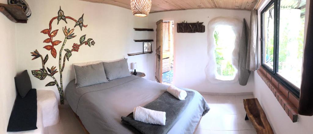 een slaapkamer met een bed in een kamer met een raam bij Finca Flora del Rio, Habitacion Las Orquideas in Pijao