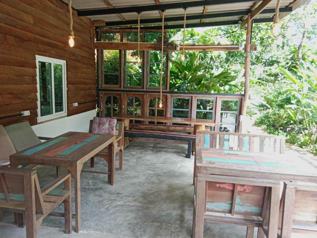 een veranda met houten tafels en banken en ramen bij My Home Koh Kood1 in Ko Kood
