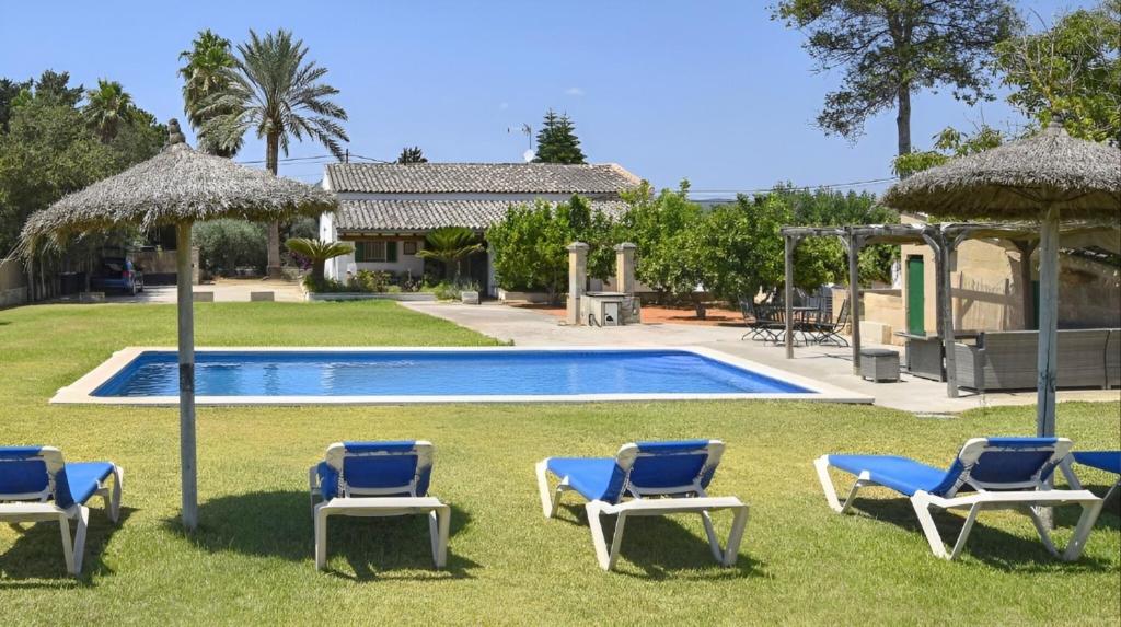 a group of chairs and umbrellas next to a swimming pool at Valls in Montuiri