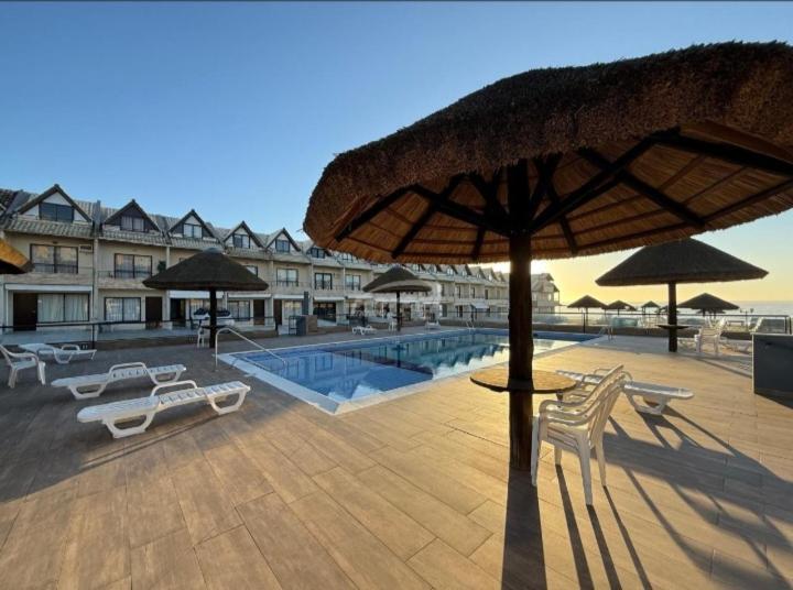 a patio with chairs and umbrellas and a pool at Condomínio Morada do sol in Barra Velha