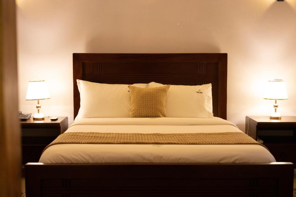 a bedroom with a large bed with two lamps at Tales Luxury in Kampala
