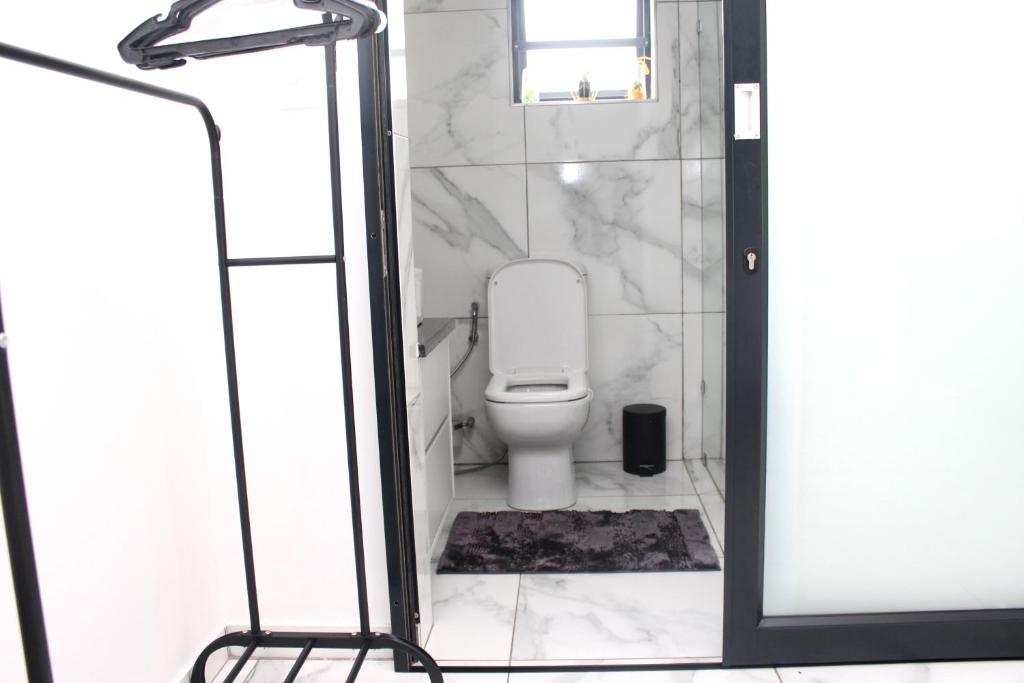 a bathroom with a toilet and a glass shower door at Tash's Place in Roodepoort
