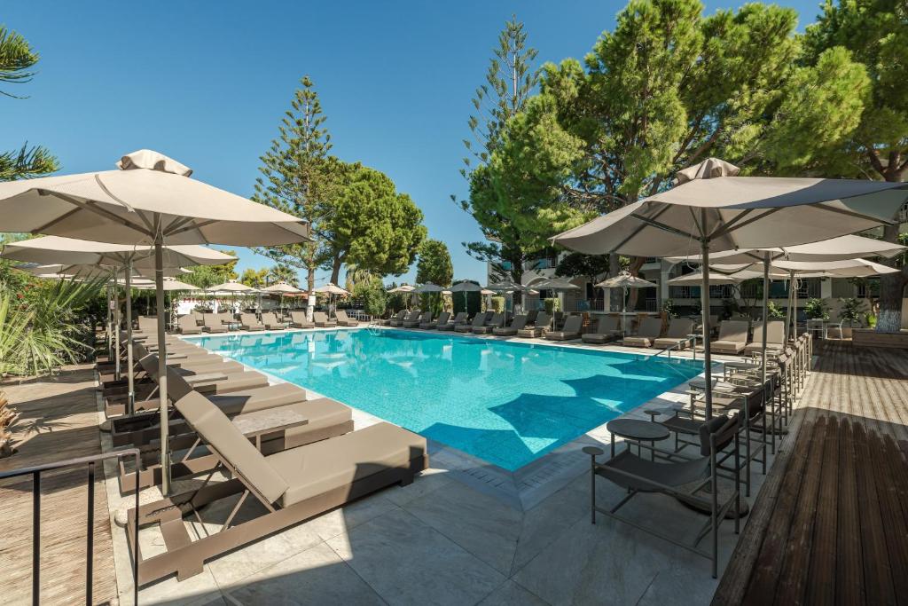 a swimming pool with chairs and umbrellas at Contessa Hotel in Argassi