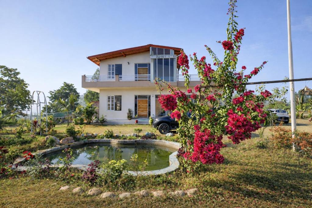 a house with a pond in the yard with flowers at Hibiscus in Kota Bāgh