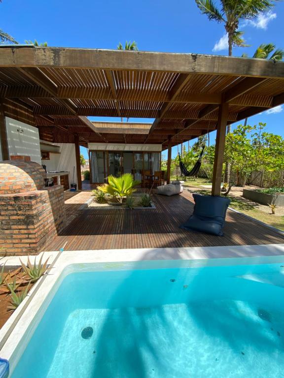 an outdoor patio with a swimming pool and a wooden pergola at Coco Ville SMG in São Miguel do Gostoso