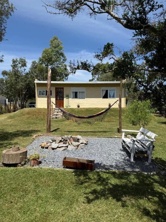 a house with a hammock and a bench in a yard at Casa en Punta Colorada con gran fondo y fogón in Punta Colorada