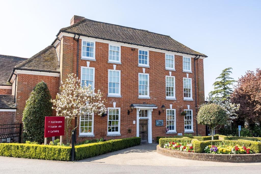 a red brick building with a sign in front of it at Windmill Village Hotel, Golf Club & Spa, BW Signature Collection in Coventry