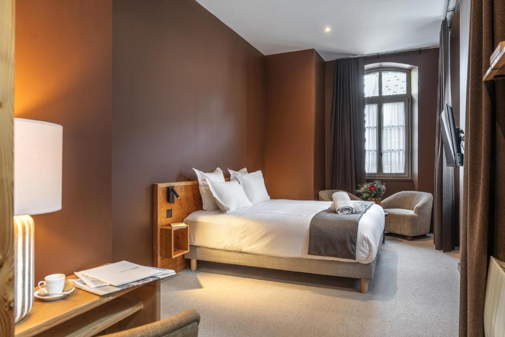een hotelkamer met een bed en een stoel bij Maison Soyeuse in Briançon