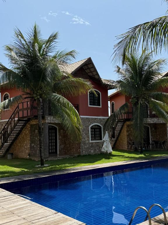a house with a swimming pool and palm trees at Chalé em Condomínio com in Aracati