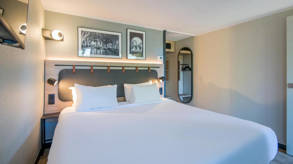 a bedroom with a large white bed with two pillows at Campanile Brive-La-Gaillarde Ouest in Brive-la-Gaillarde