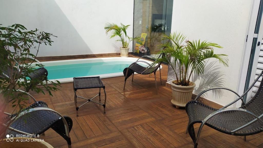 a patio with a swimming pool with chairs and plants at Espaço verão in Santa Fé do Sul