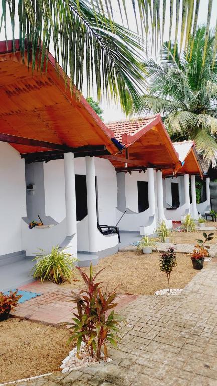 a white building with a red roof and palm trees at Econest arugambay in Arugam Bay