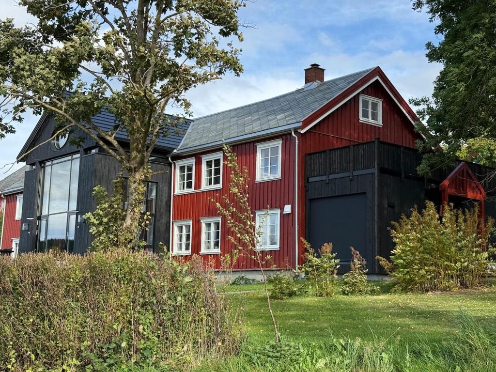 a red barn with a black garage at Apartment at NerSalberg Farm in Røra, Inderøy in Røra