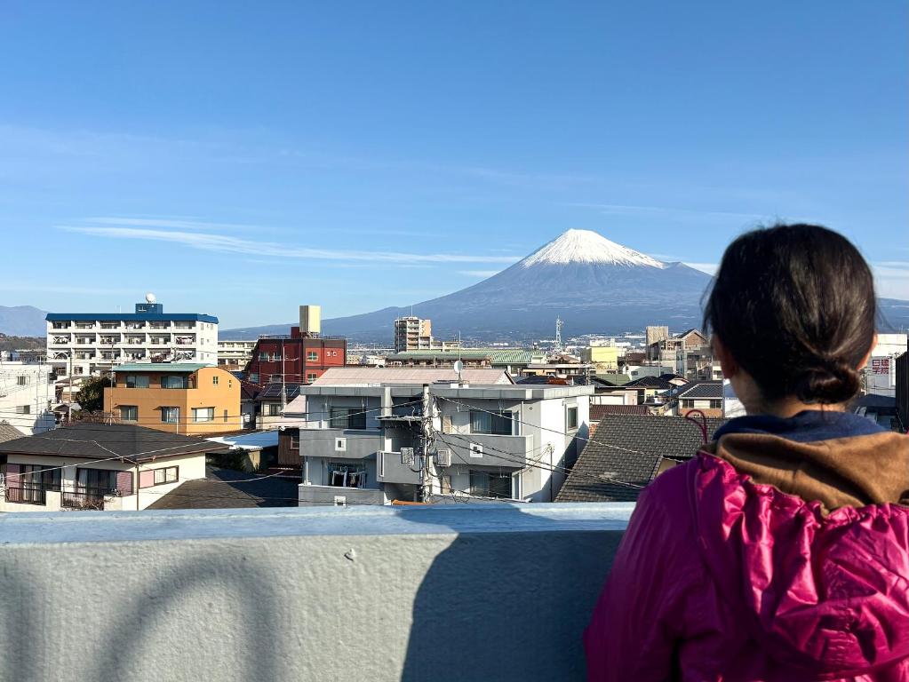 a woman sitting on a ledge looking at a mountain at GUESTHOUSE富士と碧 in Fuji