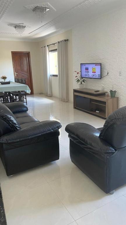 a living room with two leather couches and a tv at Casa temporada em Perocão in Guarapari