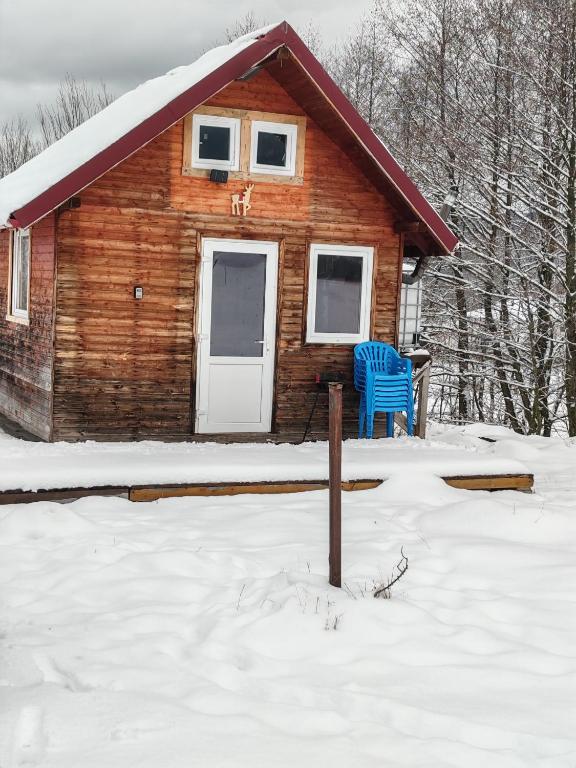 a log cabin with a blue chair in the snow at Renul Minimalist in Râşnov