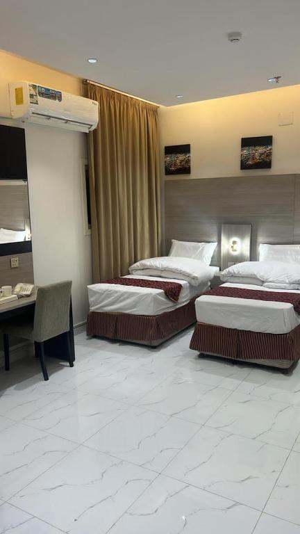 a hotel room with two beds and a desk at فندق ثرا الرواد in Abu Arish