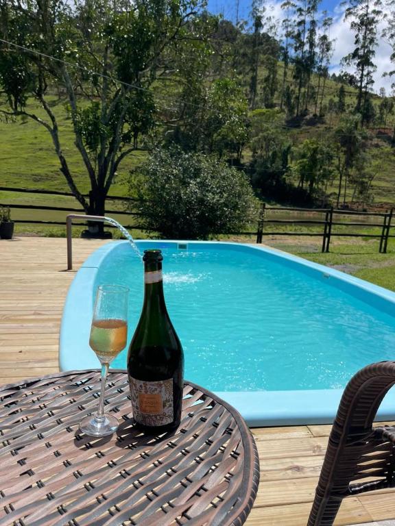 a bottle of wine sitting on a table with a glass at Sitio encantos do vale Casa in Major