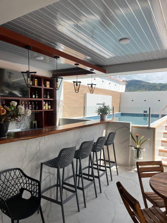 a bar with chairs and a counter with a pool at Wiky House Guaduas in Guaduas