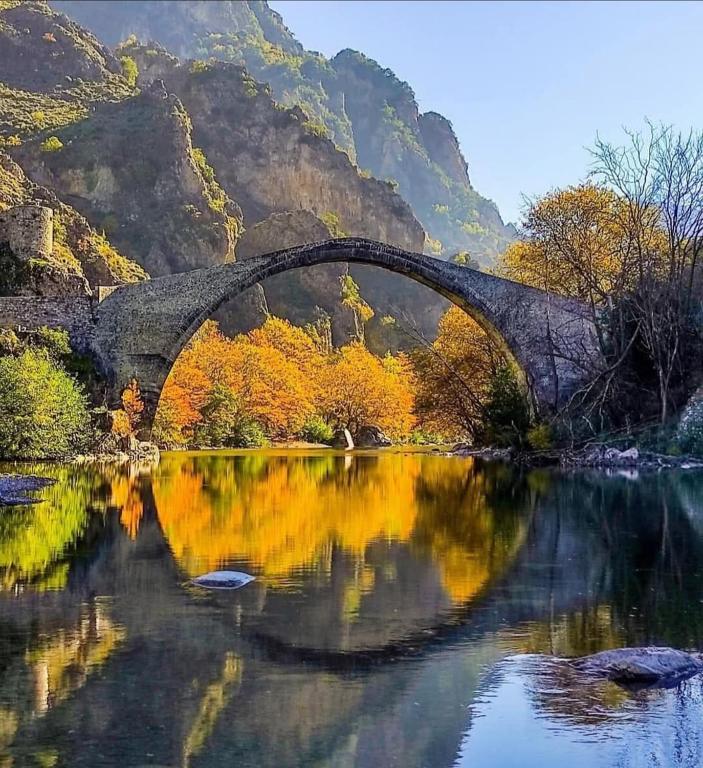 an old bridge over a river with autumn foliage at Tommy's Guest House in Konitsa