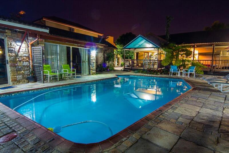 a large blue swimming pool in front of a house at Matts Rest Bnb & Self-catering in Pietermaritzburg