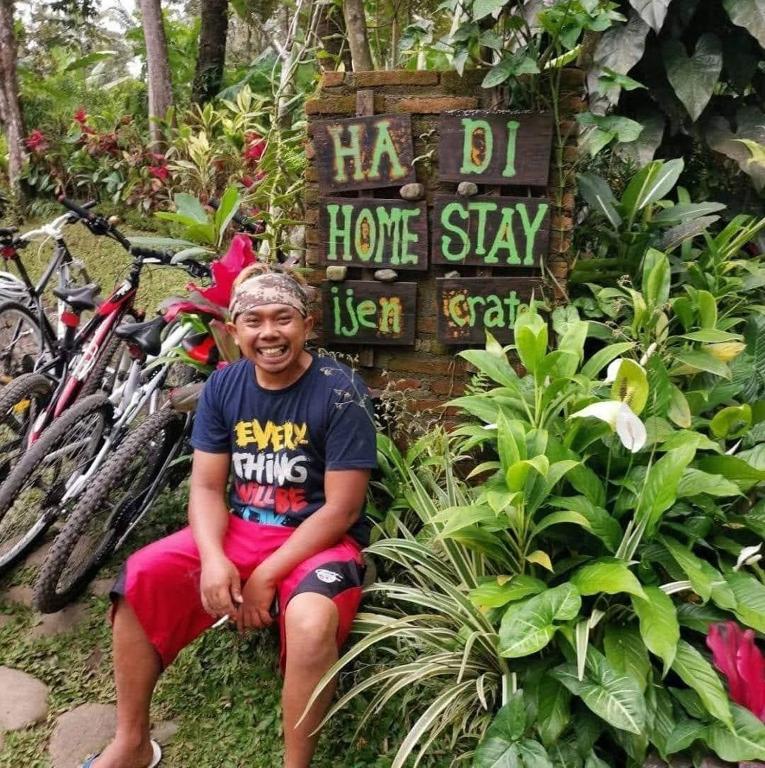 a young boy sitting in front of a sign at Hadi Homestay Garden View in Jambu