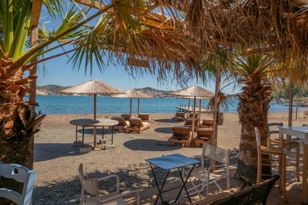 a beach with chairs and tables and umbrellas at Odyssey Eco Farm Glamping in Galatas