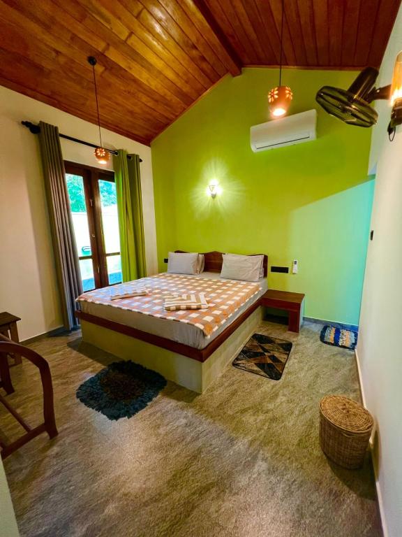 a bedroom with a bed in a room with green walls at King CoCo House in Dickwella