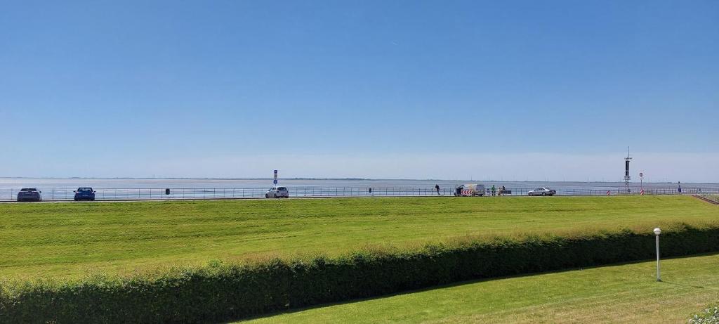 a field of grass with the ocean in the background at Exklusive Ferienwohnung am Südstrand mit Wintergarten & Hafenblick Wohnung 113 in Wilhelmshaven