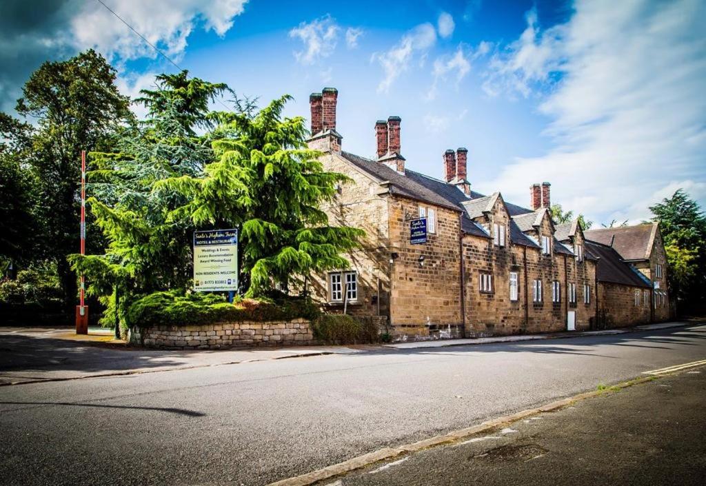 een oud bakstenen gebouw aan de kant van een straat bij Santo's Higham Farm Hotel in Alfreton